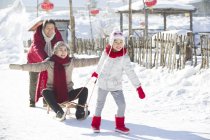 Китайские девушки тянут санки с бабушкой и дедушкой в снегу — стоковое фото