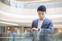 Chinese man checking time in shopping mall — Stock Photo