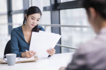 Chinese businesswoman looking at documents at meeting — Stock Photo