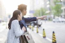 Mature couple chinois gesticulant dans la rue avec des sacs à provisions — Photo de stock