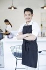 Chinese coffee shop owner standing with arms folded — Stock Photo