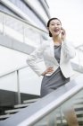 Femme d'affaires chinoise parlant au téléphone dans les escaliers de la rue — Photo de stock