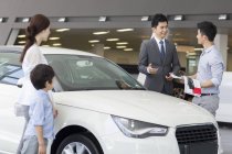 Chinese family choosing car in showroom — Stock Photo