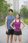 Chinese couple of joggers standing on street and smiling — Stock Photo