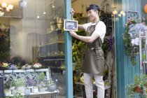 Chinese florist hanging open sign on store door — Stock Photo