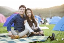 Hugging couple sitting on festival lawn — Stock Photo