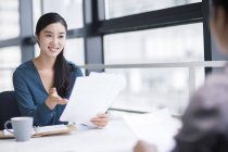 Chinese businesswoman sitting on meeting with documents — Stock Photo
