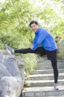 Mature chinese man stretching in park — Stock Photo