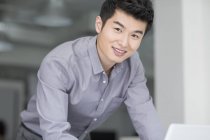 Китайский бизнесмен, опирающийся на стол и смотрящий в камеру — стоковое фото