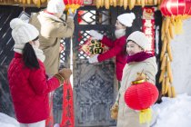 Китайские дети помогают родителям украшать ворота фонарями — стоковое фото