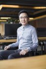 Китайский работник IT, сидящий в кресле на рабочем месте — стоковое фото