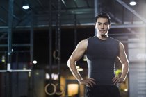 Chinese man standing at gym with hands on hips — Stock Photo