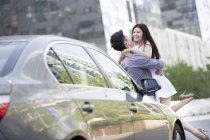 Chinesisches Paar umarmt sich neben Auto — Stockfoto