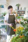 Китайский флорист стоит в цветочном магазине с ножницами — стоковое фото