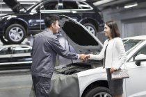 Chinese auto mechanic and car owner shaking hands — Stock Photo