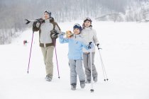 Китайские родители с сыном ходят с лыжами на плечах на горнолыжном курорте — стоковое фото