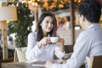 Китаянка и мужчина разговаривают с кофе в кафе — стоковое фото