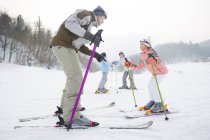 Pais chineses ensinando crianças esquiando em estância de esqui — Fotografia de Stock