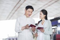 Reifes chinesisches Paar steht mit Tickets am Flughafen — Stockfoto