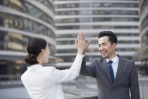 Chinese business people giving high five on street — Stock Photo