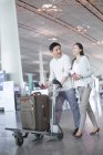 Mature chinese couple walking in airport with suitcase — Stock Photo
