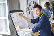 Chinese male fashion designer working with sketches in studio — Stock Photo