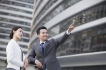 Homme d'affaires chinois dans la rue avec une femme pointant et regardant la vue — Photo de stock