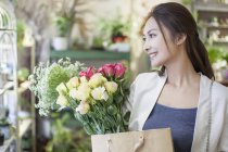 Chinesin steht mit Blumensträußen im Geschäft — Stockfoto