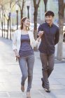 Chinese couple holding hands while walking on sidewalk — Stock Photo