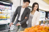 Chinese couple buying fruits in supermarket — Stock Photo