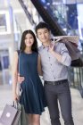 Couple chinois debout avec des sacs à provisions dans le centre commercial — Photo de stock