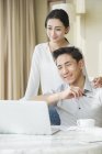 Young Chinese couple using laptop at home — Stock Photo