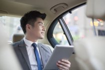 Chinese businessman using digital tablet in car — Stock Photo