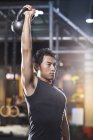 Chinese man lifting kettlebell in crossfit gym — Stock Photo