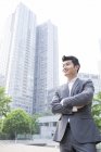 Empresário chinês olhando para longe com os braços dobrados — Fotografia de Stock