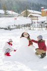 Crianças chinesas fazendo boneco de neve ao ar livre — Fotografia de Stock