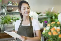 Chinese florist holding digital tablet in shop — Stock Photo