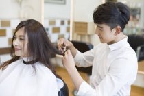 Barbeiro chinês corte cabelo cliente feminino, vista lateral — Fotografia de Stock