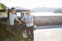 Chinese men leaning on car in suburbs and looking away — Stock Photo