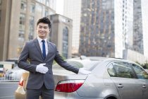 Chófer chino haciendo gesto de bienvenida en el coche - foto de stock