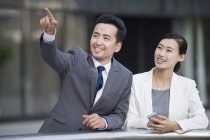 Chinese businessman pointing and looking at view with woman — Stock Photo
