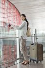 Mujer china madura esperando en el aeropuerto con billete - foto de stock
