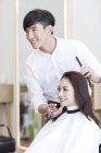 Китайский парикмахер с клиенткой, смотрящей в зеркало — стоковое фото