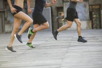 Обрезанный вид бегунов, бегущих по улице — стоковое фото