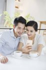 Китайська пара за допомогою смартфона в кафе — стокове фото