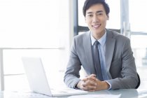 Homem de negócios chinês sentado com laptop no escritório — Fotografia de Stock