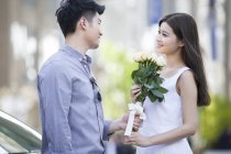 Chinese man giving flowers to girlfriend — Stock Photo