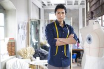 Chinese male tailor standing with arms folded in atelier — Stock Photo