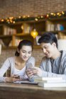 Chinese couple using smartphone in cafe — Stock Photo