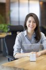 Женщина-ИТ-работница, сидящая в офисе с цифровой моделью планшета — стоковое фото